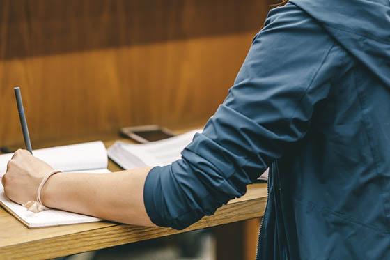 Close-up photo of a student writing in a notebook in the library